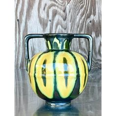 a green and yellow vase sitting on top of a table