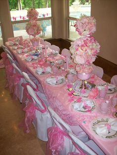 the table is set up with pink and white flowers, plates, cups, and napkins