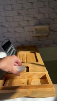 a person is using a mouse on a wooden table with a brick wall in the background