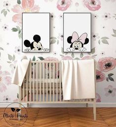 two framed pictures hang on the wall above a crib in front of a flowered wall