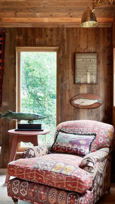 a living room filled with furniture next to a wooden wall and window covered in wood paneling