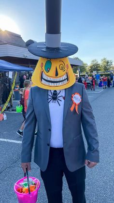 a man in a suit and top hat holding a bucket full of candy at an outdoor event