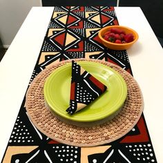 a place setting on a table with plates and bowls of fruit in the background,