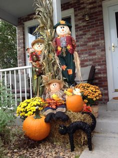 scarecrows and pumpkins are sitting on the front porch