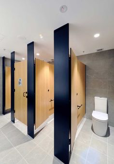 an empty bathroom with wooden stalls and white toilet in the center, surrounded by black partitions