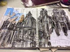 an open sketch book with drawings of buildings on the pages and one drawing of a cathedral