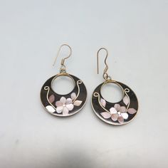 These hoop style, beautifully made black enamel and pink mother of pearl pierced earrings feature the incredible work of the Mexican metalsmiths. They are made of alpaca metal which looks like silver and wears like iron. The metal is an alloy with zinc, copper and tin. This pair is done with a floral design with pink mother of pearl, on a backdrop of black enamel. They are in excellent condition marked, Alpaca Mexico. The earrings measure 1 7/8ths inches high including the French hook fitting an Dainty Hoop Earrings, Earrings Black, Delicate Earrings, Pink Quartz, Dainty Earrings, Pierced Earrings, Jewelry Earrings Hoops, Vintage Costume Jewelry, Silver Hoops