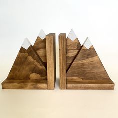 two pieces of wood with mountains cut out of them sitting side by side on a white surface