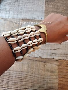 Am I the Drama? Don't pass on this unique yet beautiful tiered cowrie bracelet. Step up your arm game!! FUN FACTS: In Africa, and in the Americas, the cowrie symbolize destiny and prosperity and in many cases hold significant spiritual and even monetary value. The cowrie was an universal form of currency whose relevance weaved into the culture of Ancient African societies. (ref. Simon-Hartman.com) FEATURES ☆ Made with natural cowrie☆ Bracelet stretch to fit most wrists☆ Pairs great with any of o White Cowrie Shell Bracelet, Traditional Adjustable Shell Jewelry, Handmade Cowrie Shell Bracelets For Festivals, Bohemian Cowrie Shell Bracelet Gift, Bohemian Cowrie Shell Gift Bracelet, Adjustable Shell-shaped Bracelets For Festivals, Bohemian Shell Bracelet, Cowrie Shell Festival Bracelets, Adjustable Cowrie Shell Bracelet