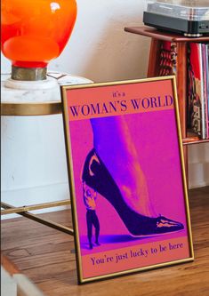 there is a woman's world sign on the floor next to a lamp and bookshelf