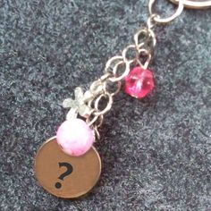 a close up of a keychain with a question mark and two charms on it