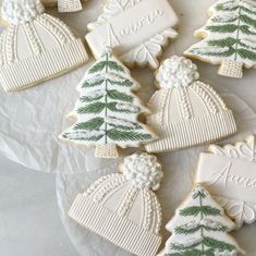 decorated christmas cookies on a plate with white frosting and green trees in the middle