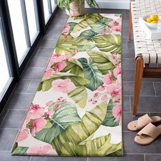 a tropical rug with pink flowers and green leaves