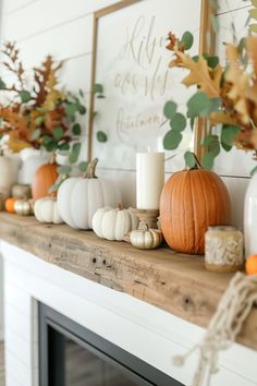 a mantle with candles, pumpkins and greenery on it in front of a fireplace