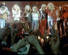 a group of people standing on top of a stage next to each other with their hands in the air