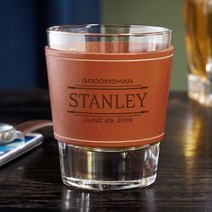 a close up of a glass on a table with a cell phone and glasses in the background