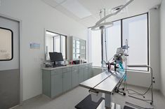 an operating room with medical equipment and large windows in the back drop off area to the right