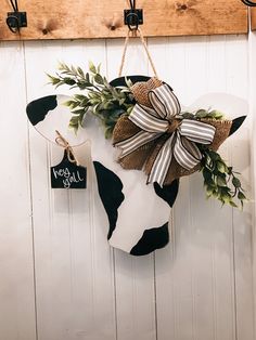 a black and white cow with a bow hanging from it's side on a wall