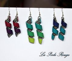 four different colored earrings hanging from hooks