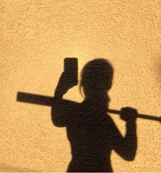 the shadow of a person holding a hammer and an object in his hand is shown