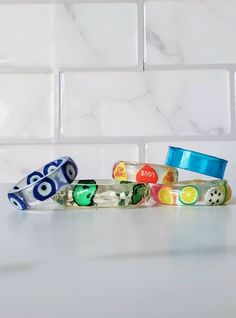 several bracelets are stacked on top of each other in front of a white tile wall