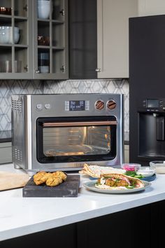 a silver microwave oven sitting on top of a counter next to a plate of food