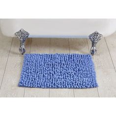 a blue rug sitting on top of a wooden floor next to a white bath tub