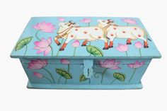 a painted wooden box with flowers and cows on the lid, sitting in front of a white background