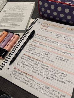 notebooks and pens sitting on top of a table next to an open book with writing