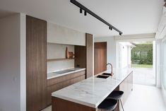 a kitchen with marble counter tops and bar stools in front of an open window