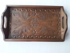 an old wooden tray with carved designs on it's sides and handles, hanging from the wall