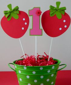 a green bucket filled with strawberries on top of a table