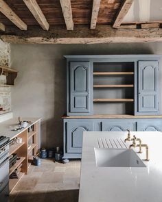 a kitchen with blue cupboards and white counter tops in the middle of the room