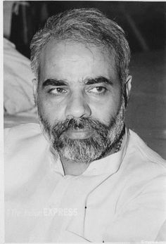 an old photo of a man with a beard wearing a white shirt and looking at the camera