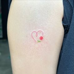 a small tattoo on the back of a woman's left arm with a flower in the shape of a heart