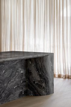 a black marble table in front of a curtained window with sheer curtains behind it