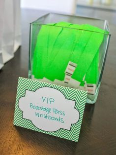 a glass container filled with green teabags sitting on top of a wooden table next to a sign