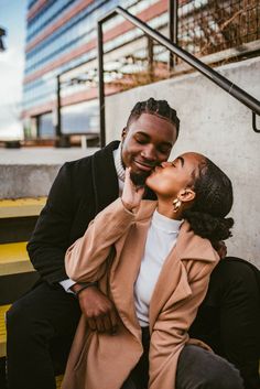 a man and woman sitting on steps kissing each other with their noses close to one another