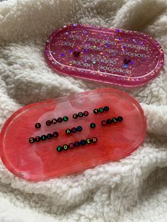 two plastic trays sitting on top of a white blanket covered in beads and sequins