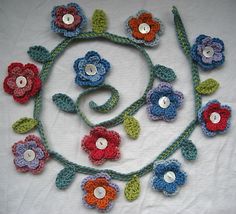 crocheted flowers and leaves are arranged on a white surface with buttons in the center