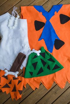 several pieces of cloth are laid out on a wooden floor, including an orange and blue shirt