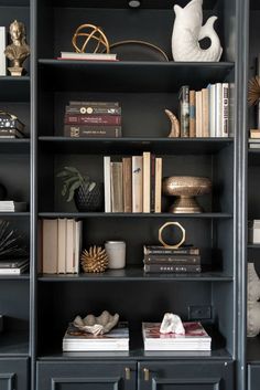 a black bookcase with many books and vases on top of it, along with other decorative items