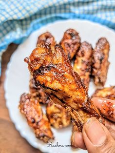 someone is holding up some chicken wings on a plate