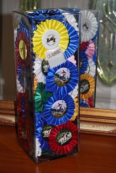 a clear box filled with lots of different colored ribbons on top of a wooden table