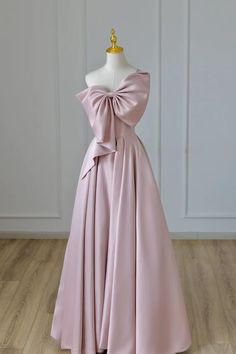 This blush pink gown is a sartorial tribute to grace and femininity. Crafted from luxurious satin, the gown features a single-shoulder design that exudes elegance. The bodice is sleek, contouring gracefully along the bodys natural lines, and leads to an oversized bow detail on the shoulder, which serves as the centerpiece of the ensemble. The bow is expertly constructed, adding dimension and a dramatic flair that is both modern and timeless.The gowns waist is cinched before it unfolds into a ful Prom Dress With Bow, Bow Gown, Satin Long Prom Dress, Satin Evening Dresses, Pink Prom Dress, Formal Evening Dress, Pink Prom, فستان سهرة, Pink Prom Dresses