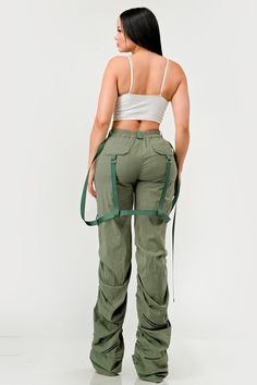 This distinct fashion choice merges the practicality of traditional utility wear with a touch of contemporary finesse. The pants are an ode to the functional attributes of cargo garments, designed to be robust with ample pocket space for practical use. The ruched detailing along the legs introduces a unique aesthetic twist, creating a gathered, textured effect that adds visual interest and a flair of modern sophistication. The inclusion of sleek, tonal belt straps further accentuates the waistli Khaki Utility Parachute Pants With Loose Fit, Military Cargo Pants With Multiple Pockets For Spring, Versatile Khaki Cargo Pants For Spring, Spring Military Style Parachute Pants With Cargo Pockets, Spring Military Parachute Pants With Cargo Pockets, Spring Military Cargo Parachute Pants, Green Utility Bottoms With Multiple Pockets, Spring Khaki Cargo Pants With Belt Loops, Spring Utility Cargo Pants With Belt Loops