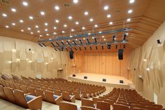 an empty auditorium with rows of seats in front of the stage and lights on the ceiling