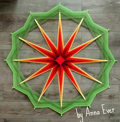 an origami star made out of green and red paper on a wooden floor