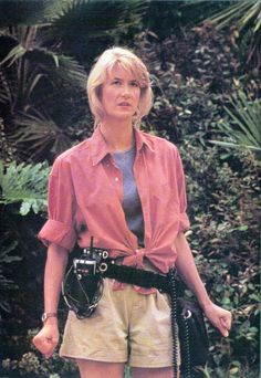 a woman in shorts and a pink shirt holding a camera