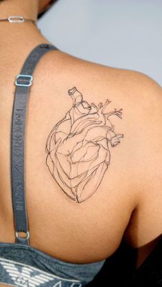 a woman's back with a tattoo on her shoulder and a heart in the middle